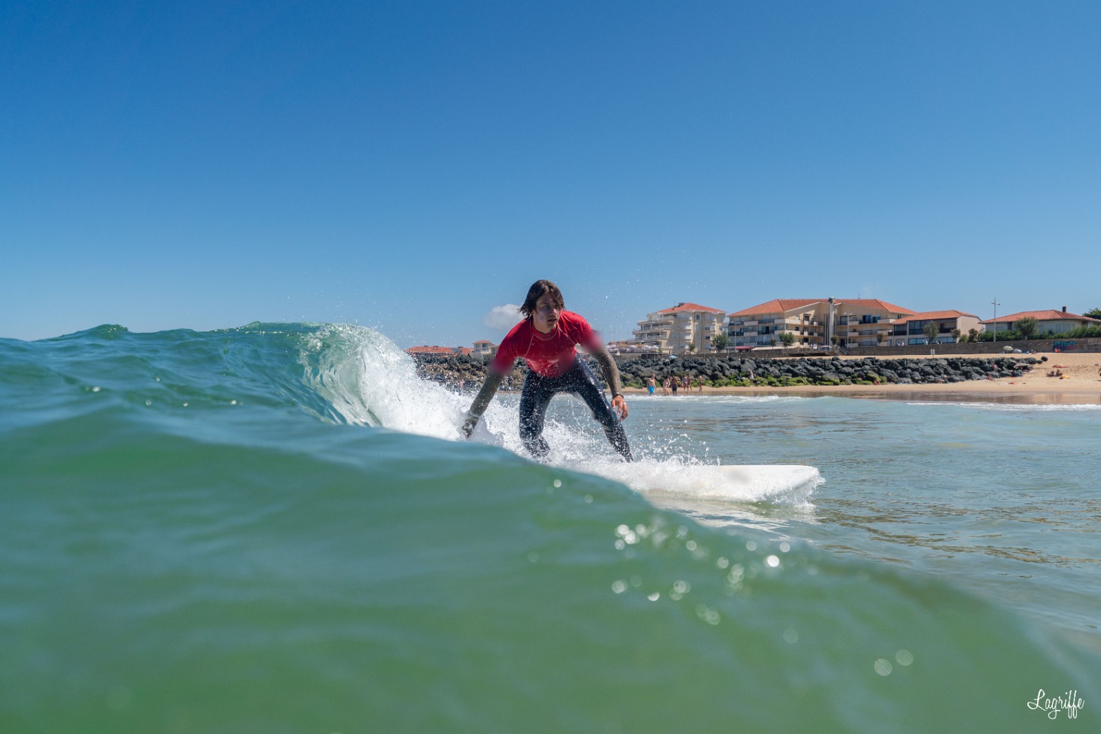 Surfeuse sur une vague, front de mer en arrière-plan