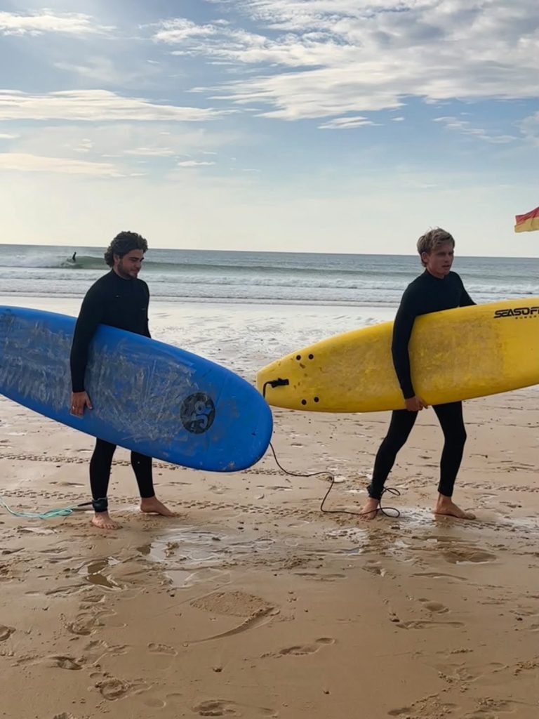 Deux surfeurs marchant sur le sable mouillé avec leurs planches