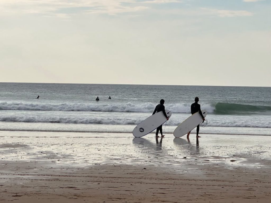 Deux surfeurs face aux vagues en fin de journée, planches à la main