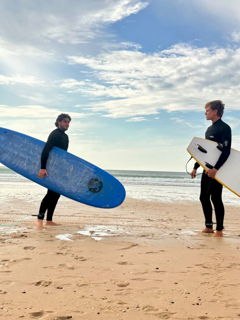 Deux surfeurs face à face au bord de l’eau, planches sous le bras